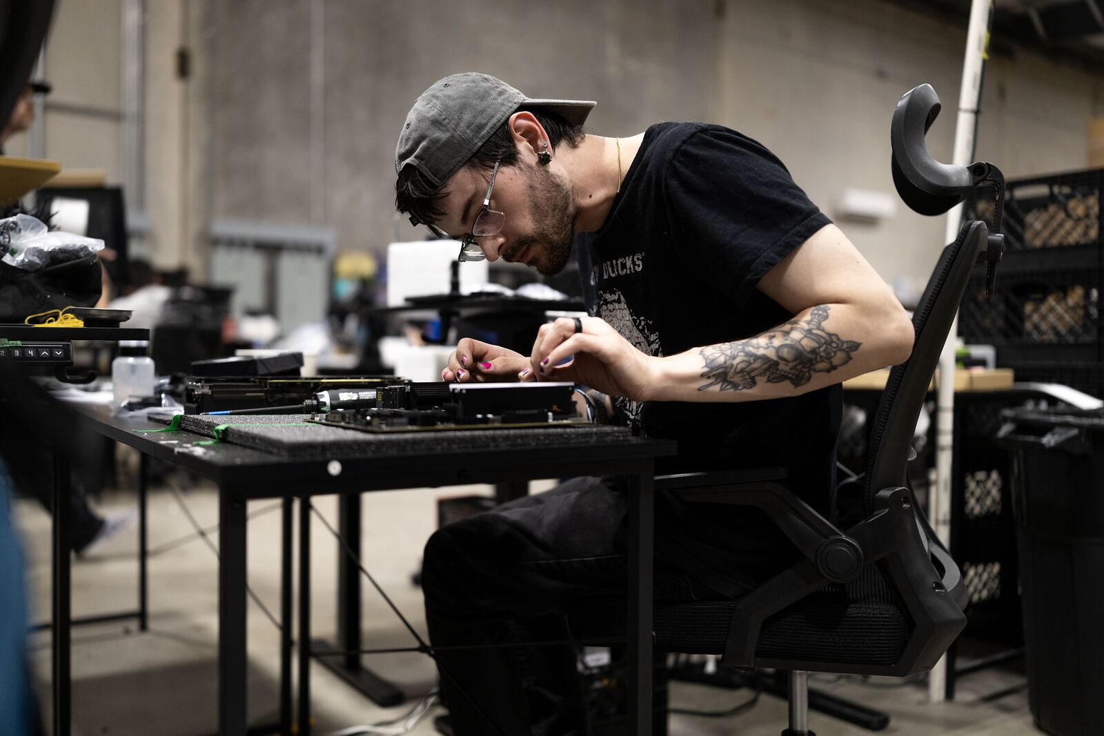 An engineer working on a server board at a lit bench.